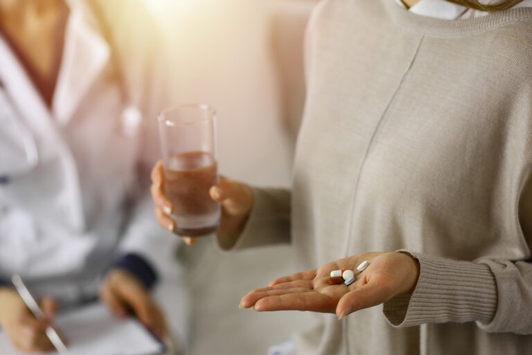 Woman with pill on her hand and a doctor