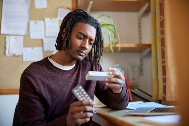 Young adult man reading prescription medication box