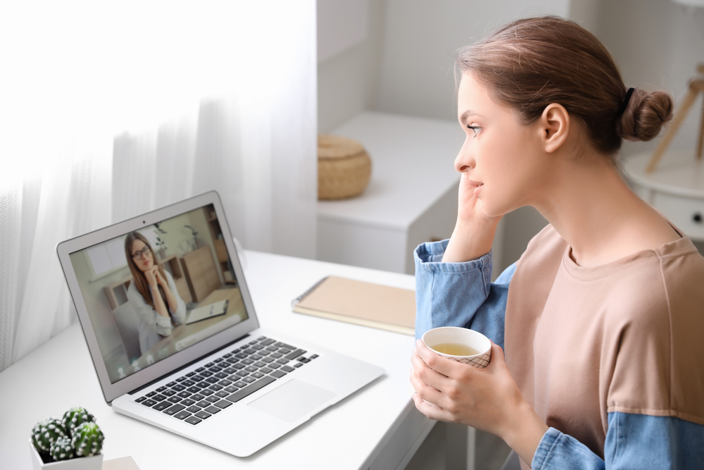 Stressed young woman asking psychologist for advice online at home