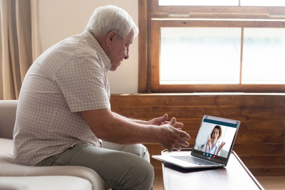 Older, somewhat heavy man talking to doctor on laptop. He's wondering how to ask your doctor for weight loss pills.